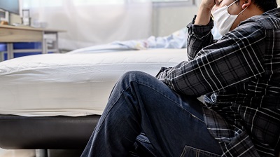 man sitting next to his bed